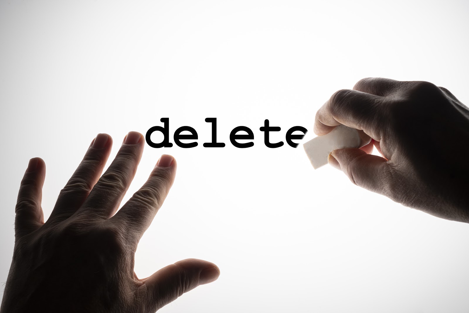 erasing the word Delete with a rubber on a backlit surface